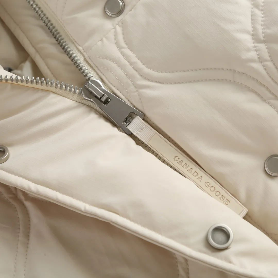 P1060 Canada Goose hooded down jacket fabric selection; nylon fabric is known for its high strength, excellent wear and tear resistance, and excellent durability. At the same time, it is light in texture, easy to move, and has excellent water-repellent function, which can effectively deal with light rain and humidity. Technology: Double-needle quilting technology is used. Double-needle quilting technology is a sophisticated sewing technology. Its core feature is to use two needles to quilt at the same time to form two parallel stitches. This design not only makes the quilting lines visually more three-dimensional, regular and refined, but more importantly, it greatly enhances the firmness of the sewing. The double lines in parallel form a more stable structure, which can effectively lock the internal filling and significantly prevent it from shifting, accumulating or velveting during wearing or washing, thereby ensuring that the thermal insulation layer is evenly distributed without cold spots, and comprehensively improves the durability and thermal efficiency of the product.    High-quality filling: It is filled with 90% selected white duck down, weighing 170g, ensuring fluffy rebound, lightness and warmth.  Accessories: one-to-one customized three-standard, one-to-one customized zipper, one-to-one customized hardware
